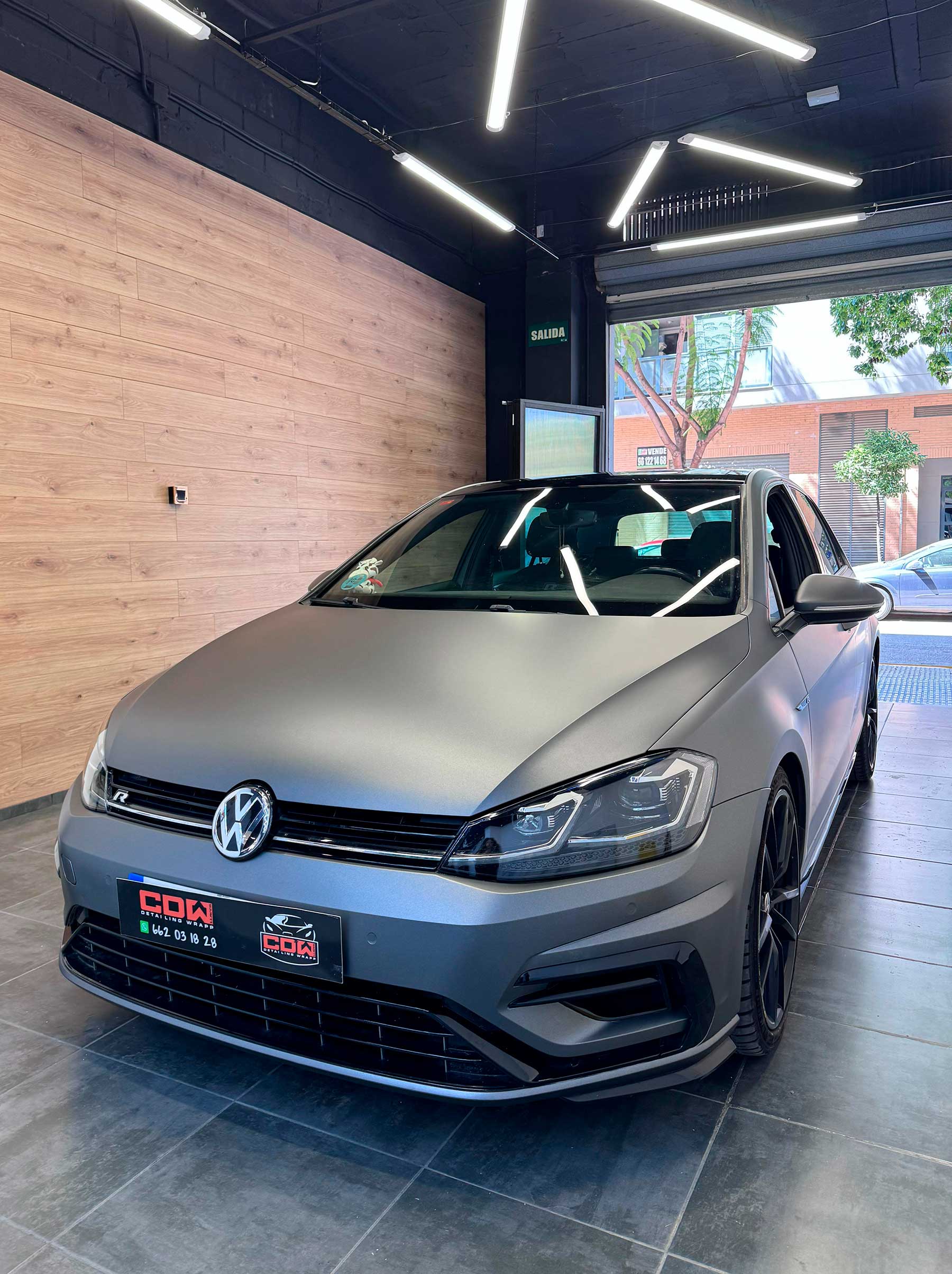 Volkswagen Golf envuelto en vinilo gris mate dentro del taller CDW Llacer, acabado OEM y detalles en negro.3