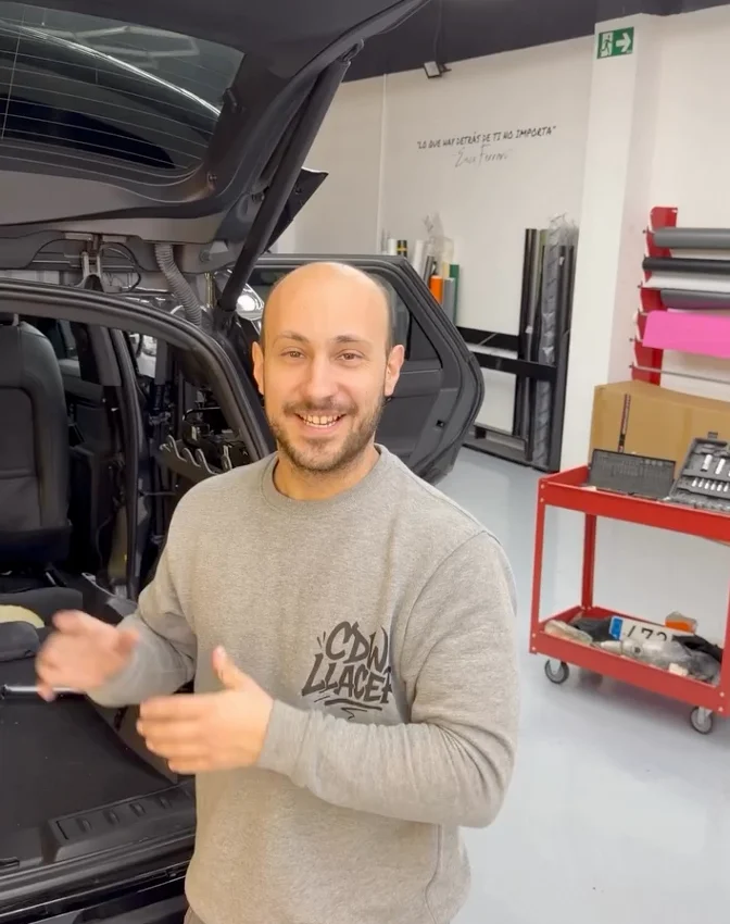 Luis Llacer hablando frente a un coche en el taller